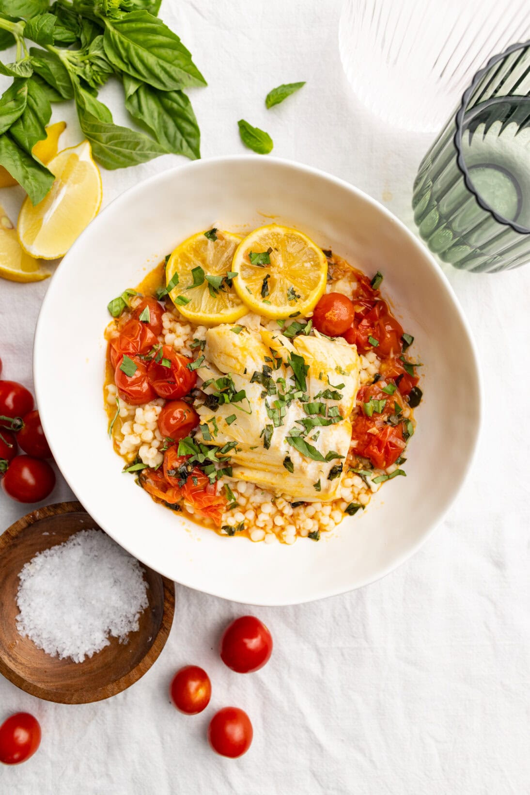 a bowl of tomato poached cod over couscous