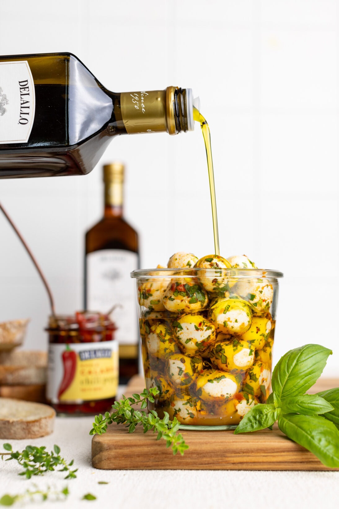 pouring olive oil over a jar of marinated mozzarella balls