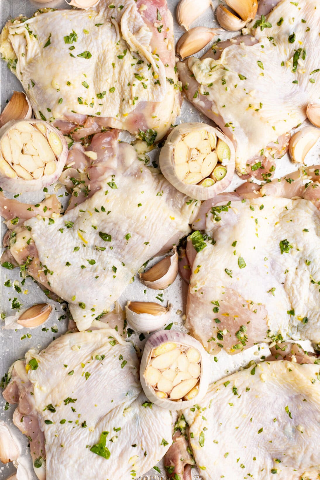 fully seasoned un cooked chicken thighs on a sheet pan ready to go into the oven