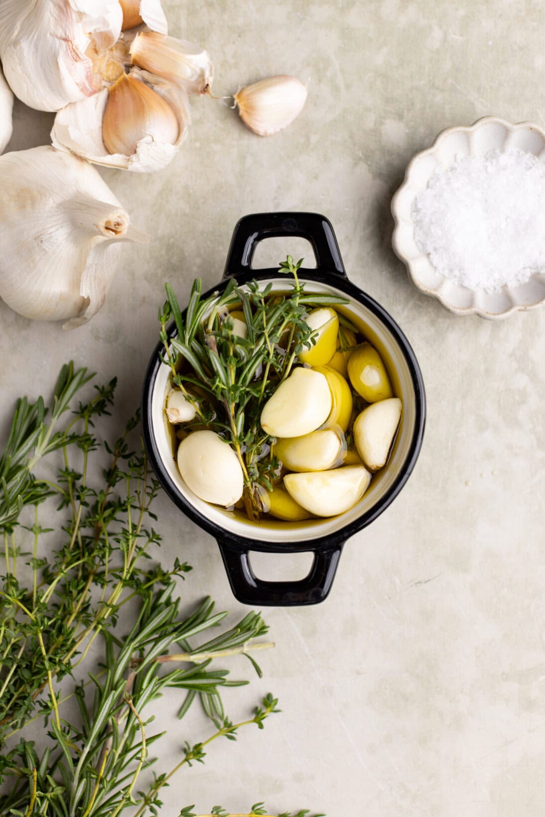 garlic mostly submerged in olive oil in an oven safe dish. Not cooked.