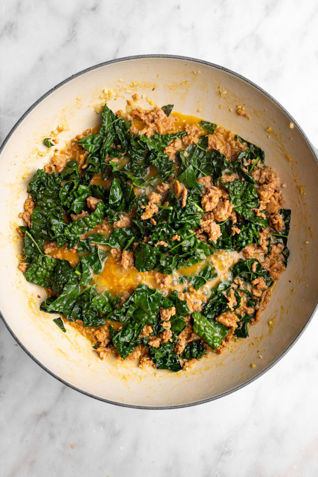 step by step photo: added back the sausage and kale. letting the kale wilt. 