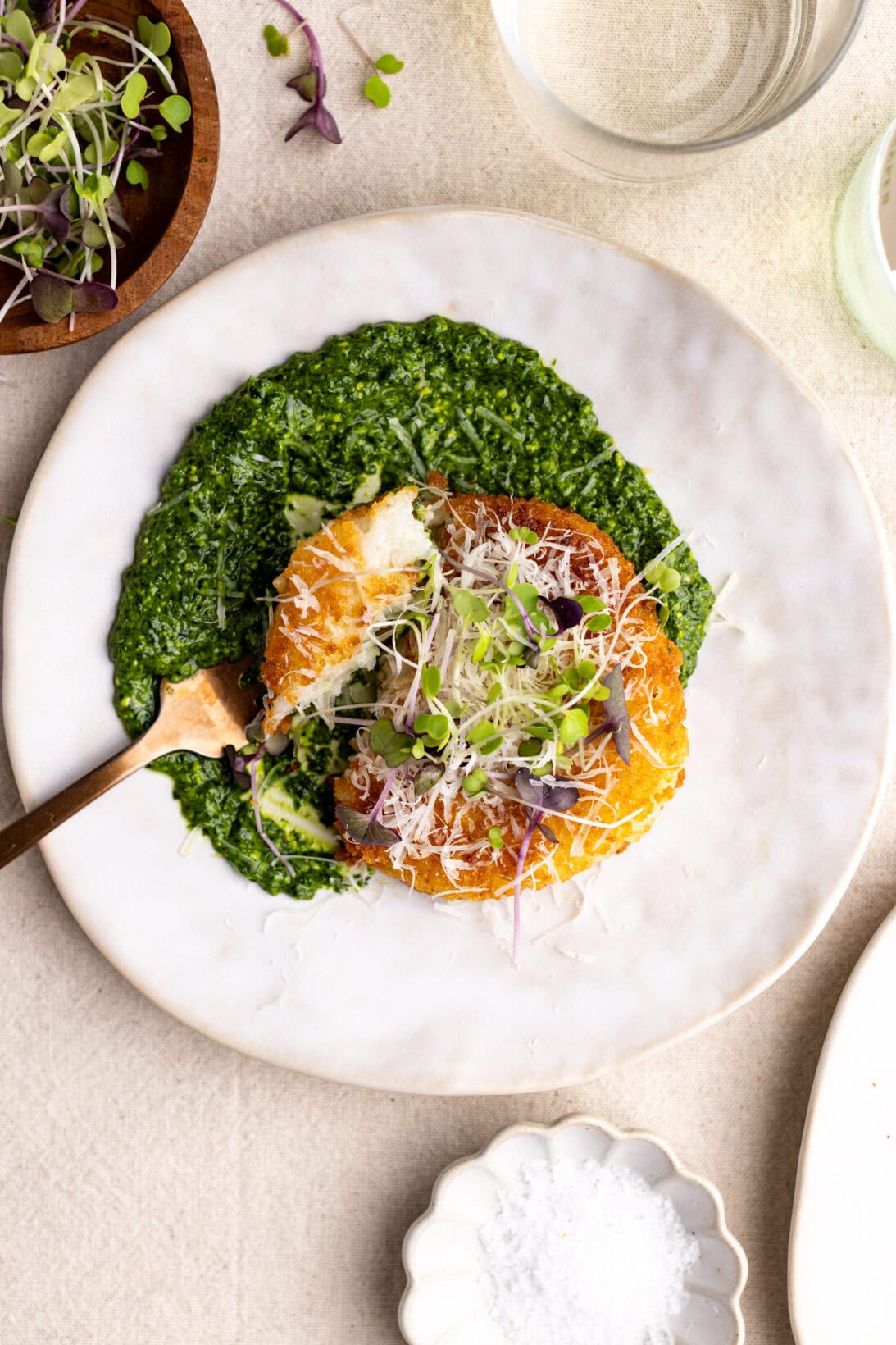 a fork full of risotto cake topped with parmesan cheese.