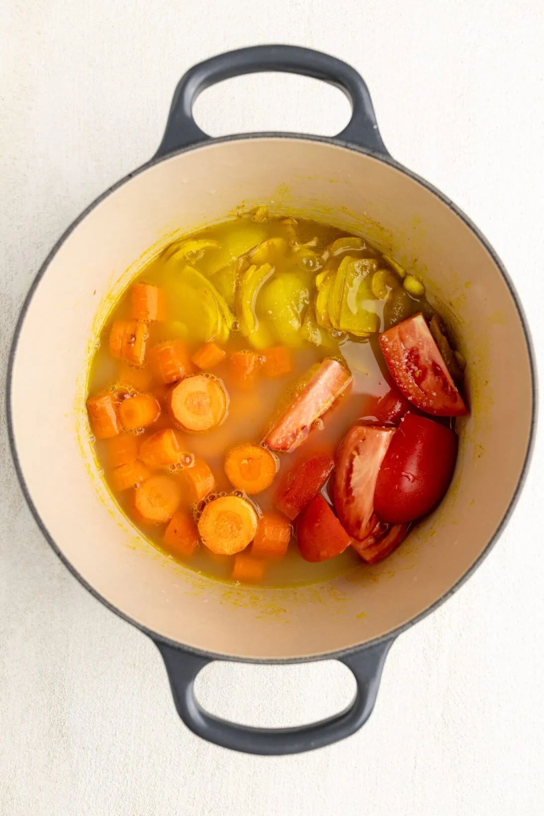 step by step: adding the carrots, tomatoes and broth to the pot to simmer. 