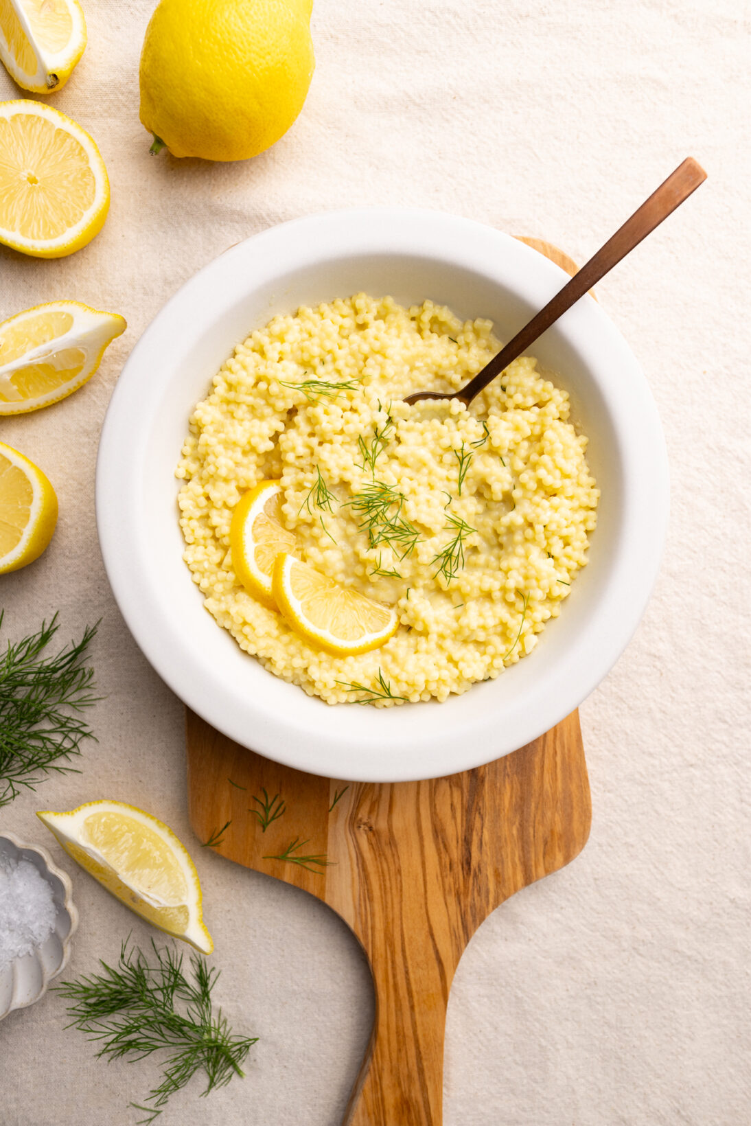 A bowl of lemon pastina garnished with lemon and dill. 