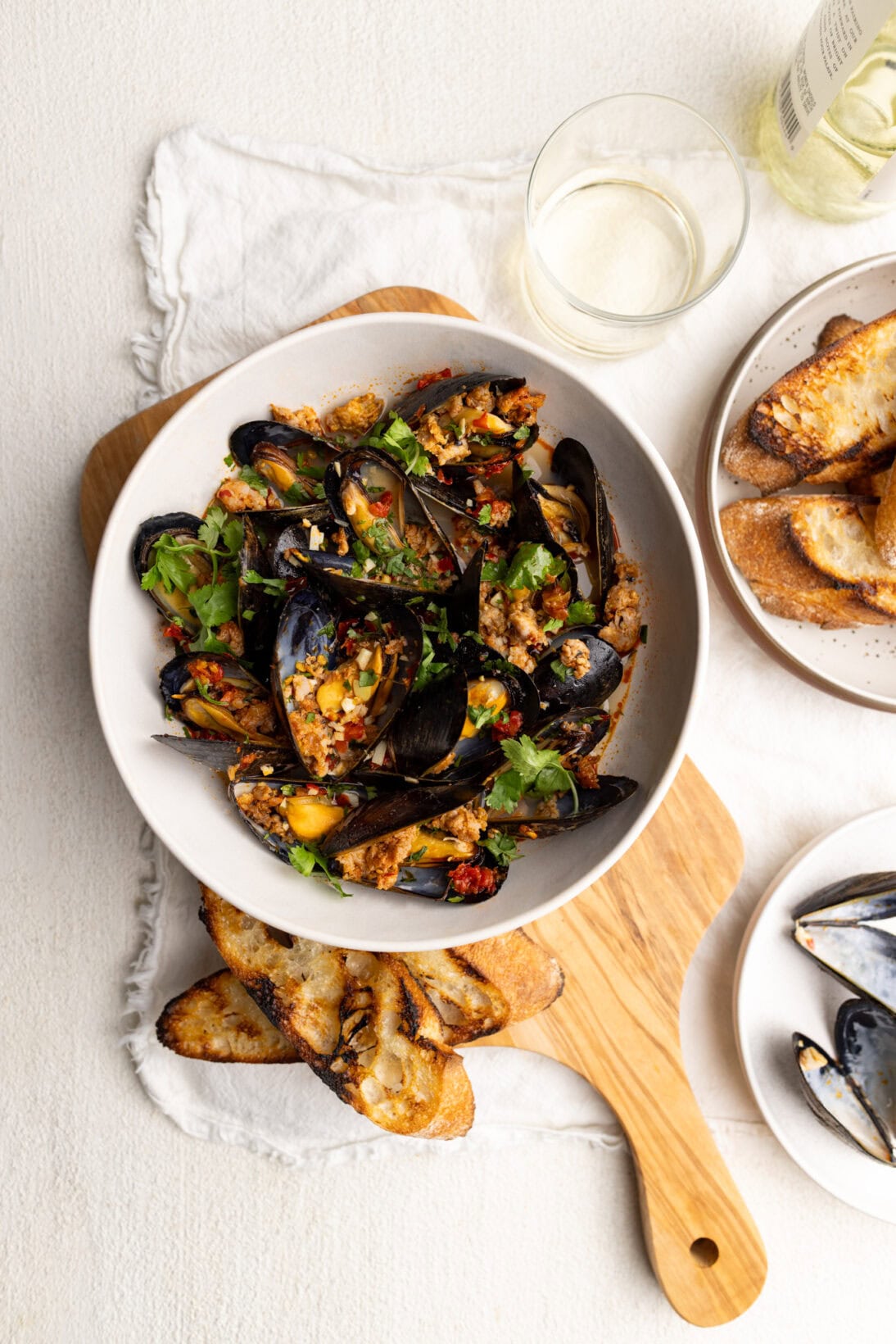 a bowl of spicy mussels in white wine sauce, with grilled bread.