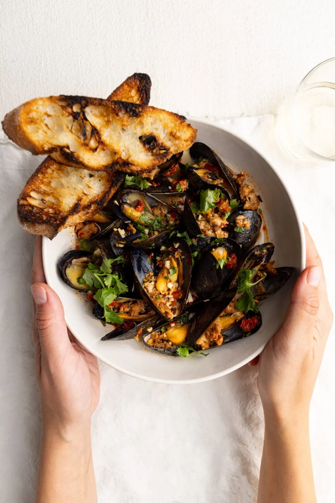 a bowl of spicy mussels in white wine sauce, with grilled bread.
