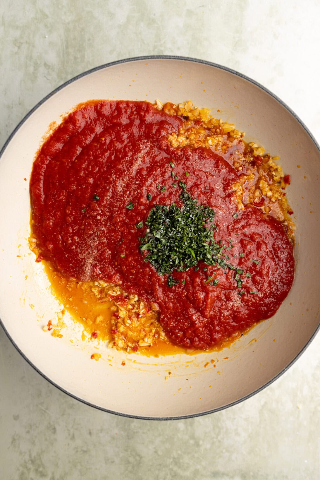 step by step spicy marinara: adding the crushed tomatoes and basil.