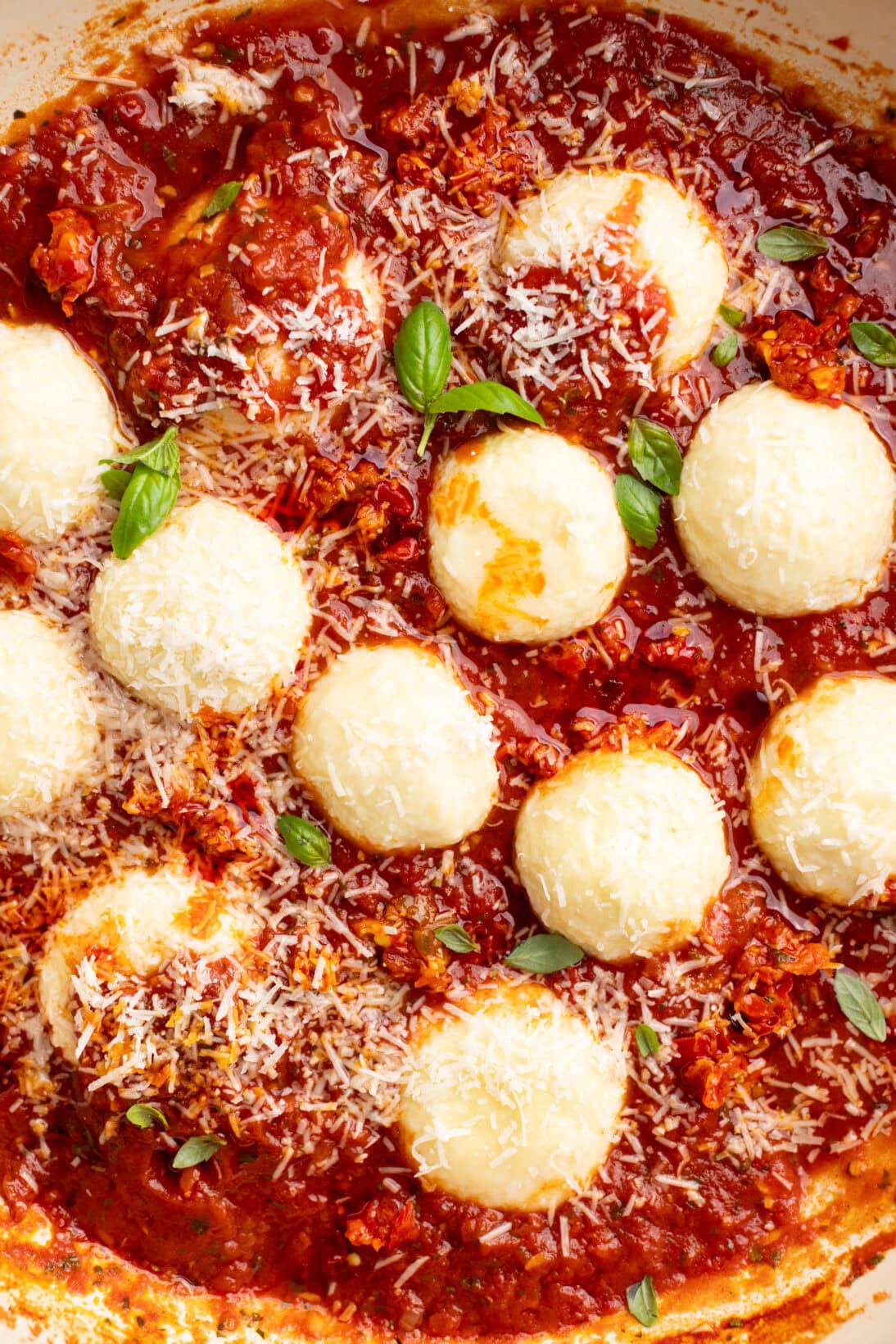 ricotta gnudi in a spicy red sauce topped with Parmesan cheese.