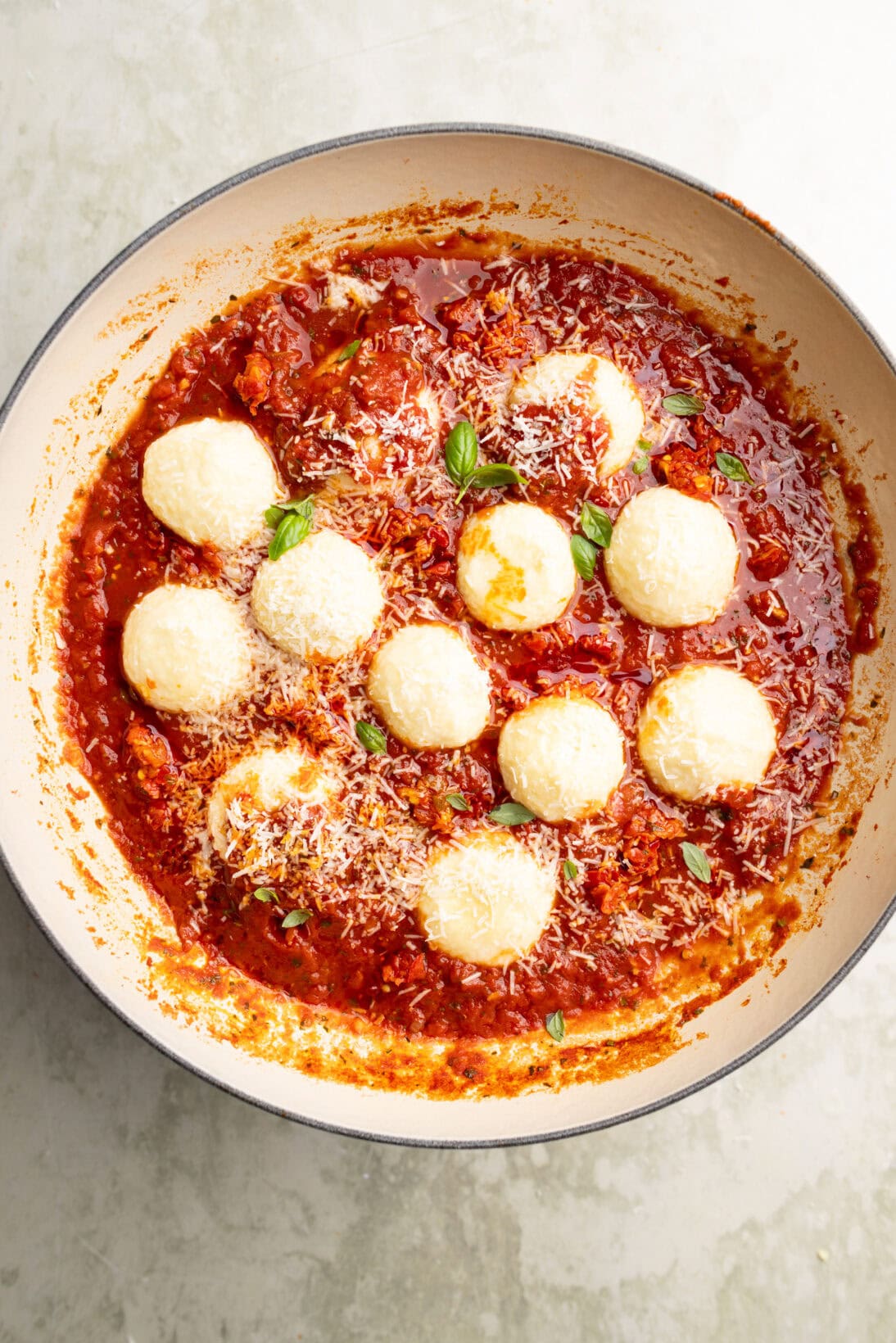 ricotta gnudi in a spicy red sauce topped with Parmesan cheese.
