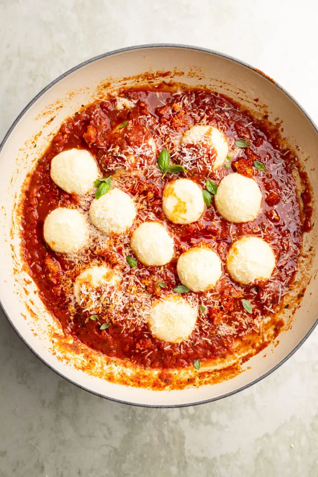 ricotta gnudi in a spicy red sauce topped with Parmesan cheese.