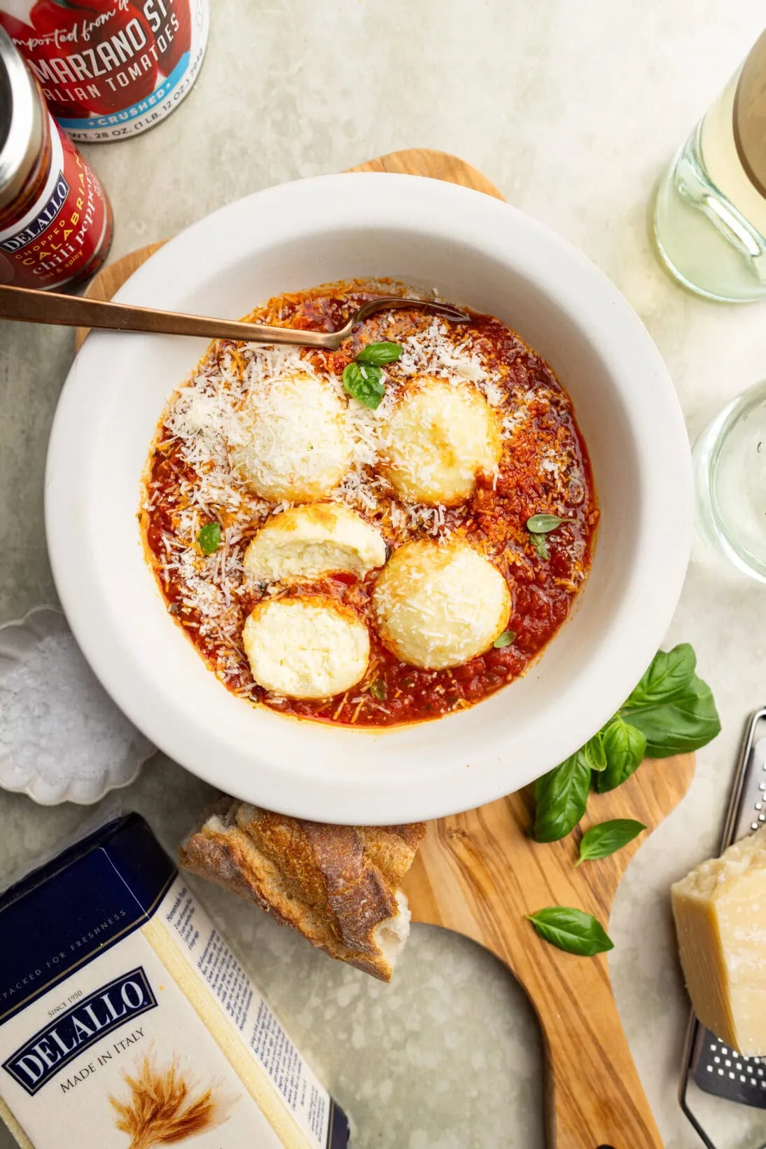a bowl of ricotta gnudi in a spicy red sauce topped with Parmesan cheese