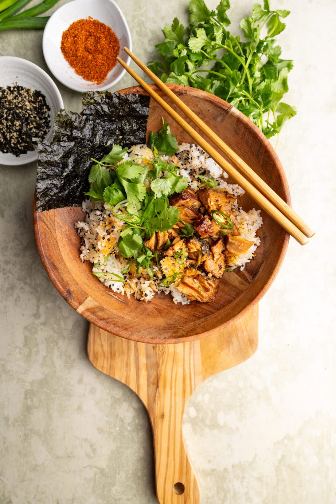crispy rice bowl topped with salmon, green onions, cilantro, and nori sheets.