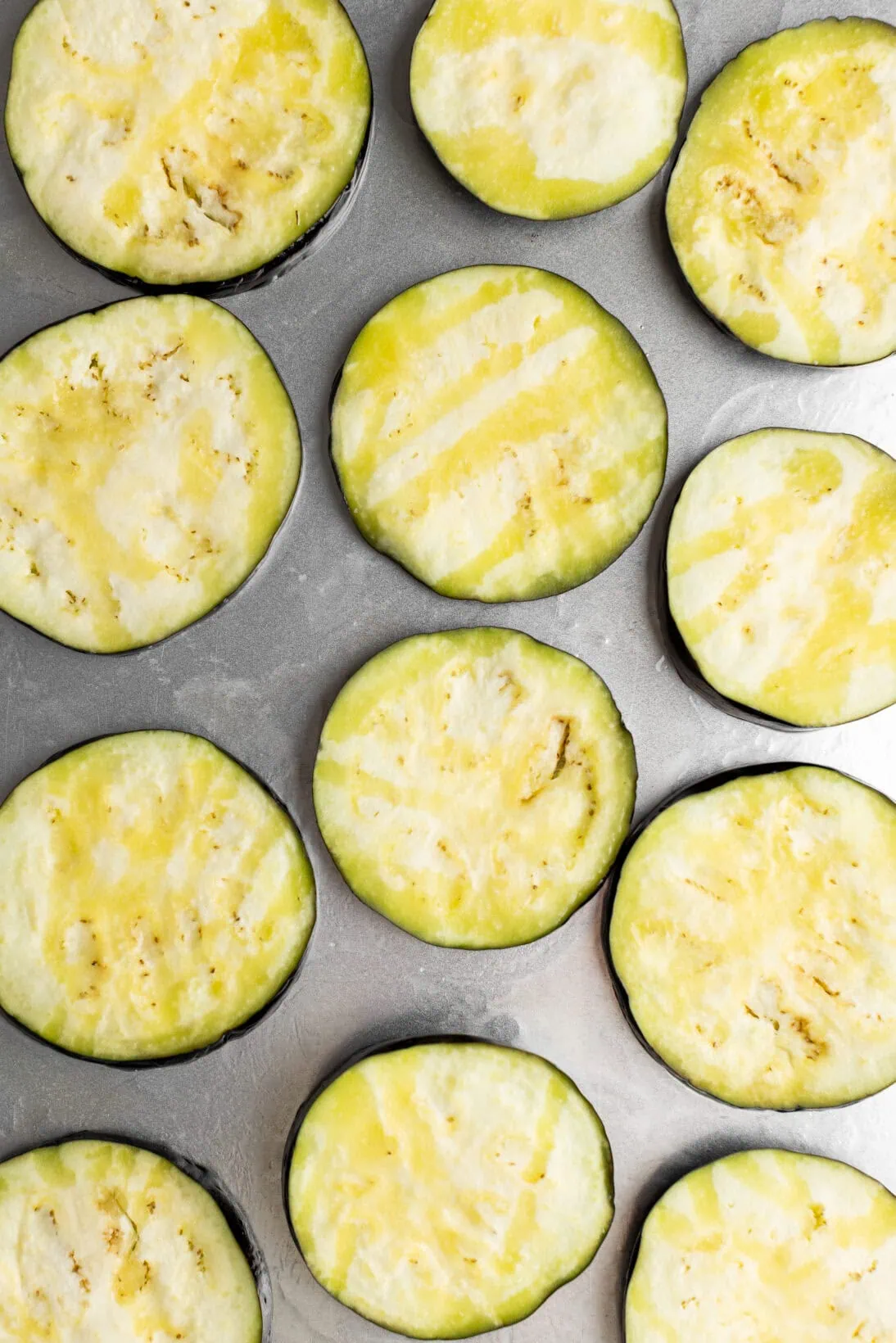 oiled and seasoned raw eggplant on a sheet tray