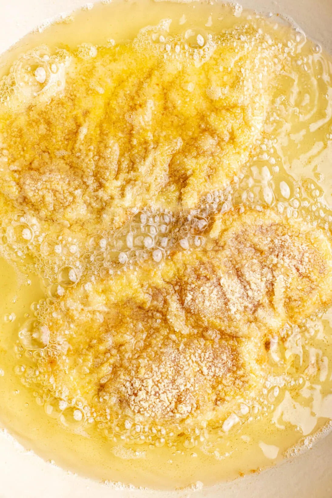 two chicken cutlets frying