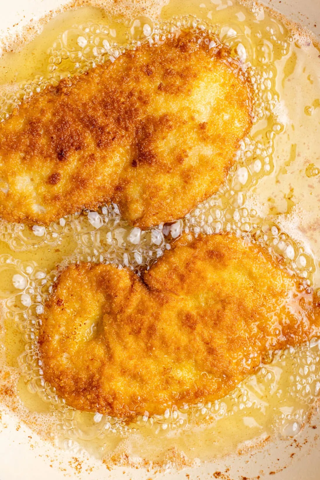 two chicken cutlets frying