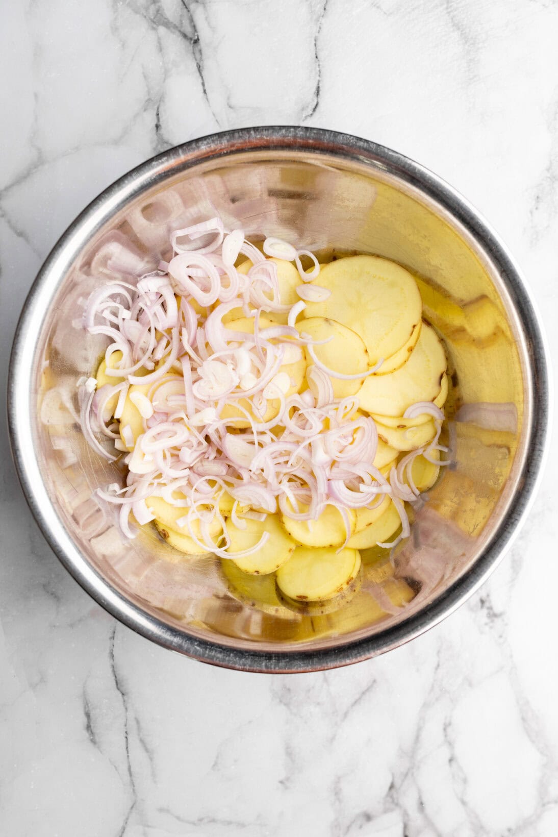 scalloped potatoes in a bowl with shallots ready to season.
