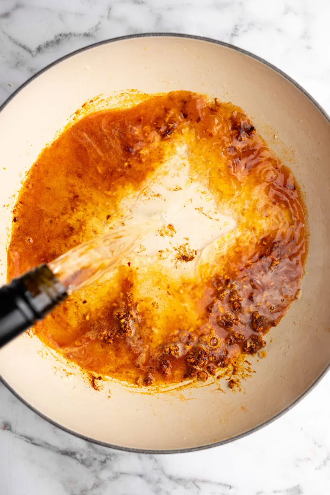 step by step:  adding the wine to the pot of garlic, oil, and spices.
