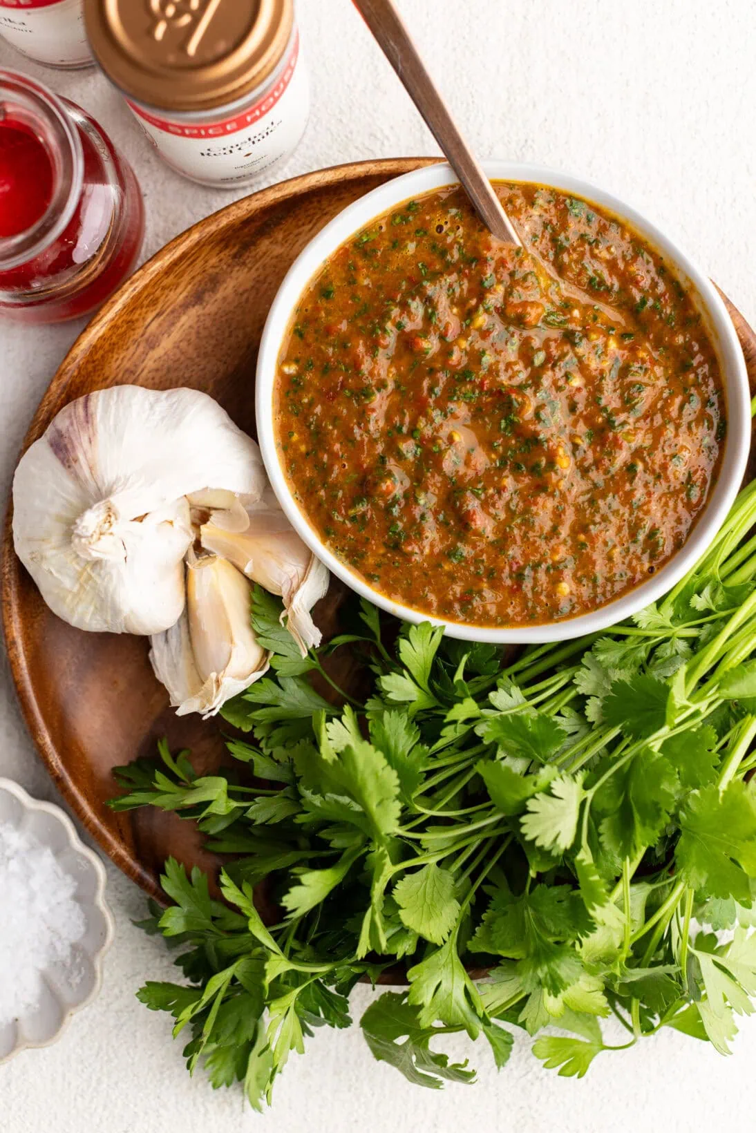 red chimichurri in a bowl surrounded by ingredients. 