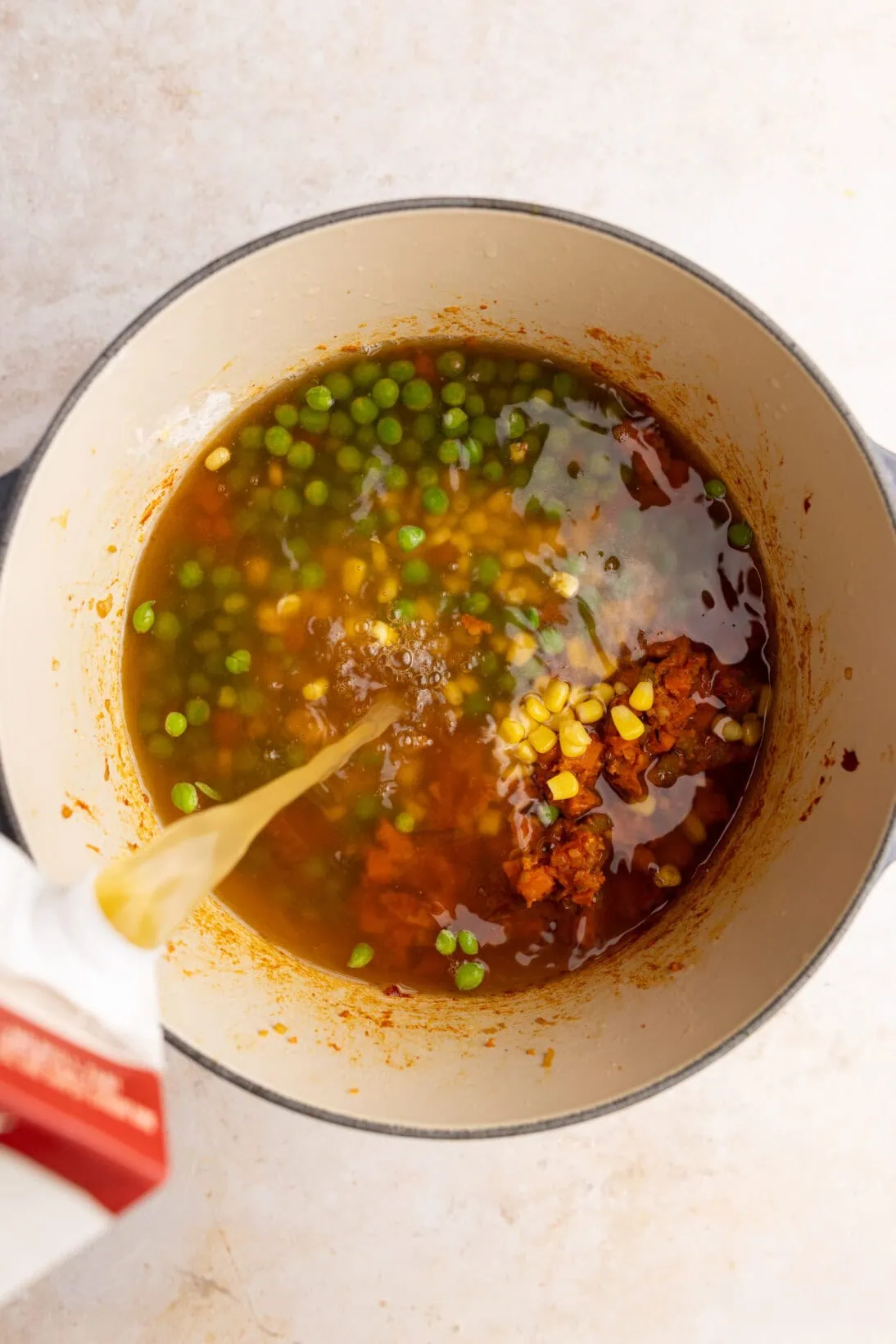 step by step: adding the broth, peas and corn.