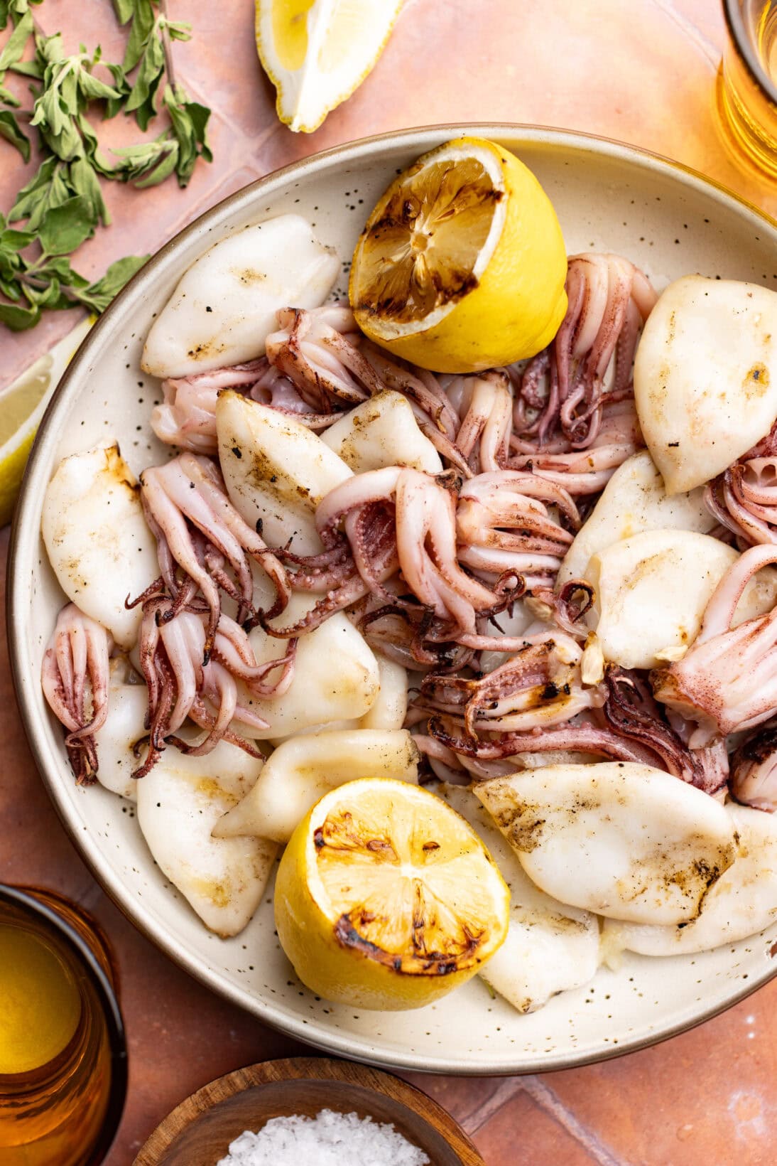 a low bowl of grilled squid, tubes and tentacles with grilled lemon.