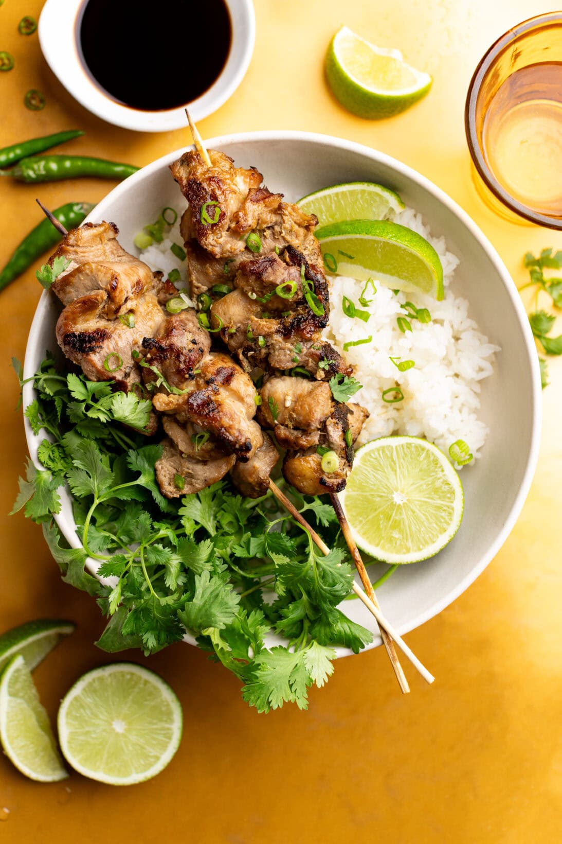 a bowl of sushi rice and moo ping skewers.