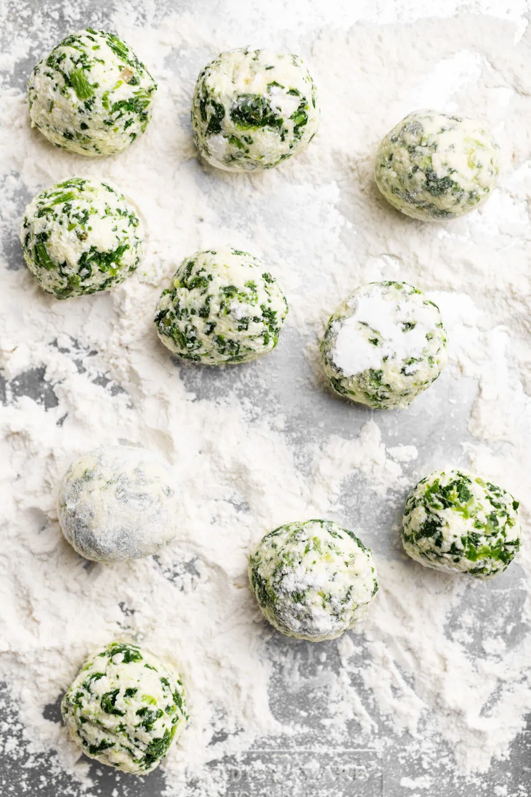 rolling the spinach and ricotta gnudi in all-purpose flour.