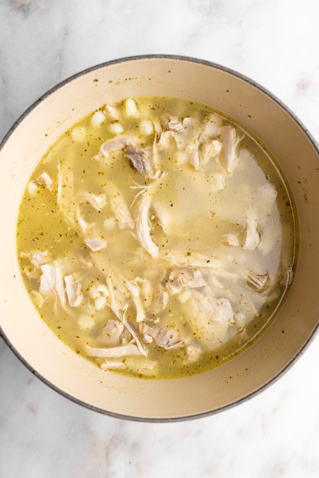 step by step: cooking the chicken pozole after 20 minutes when the chicken starts to break apart.