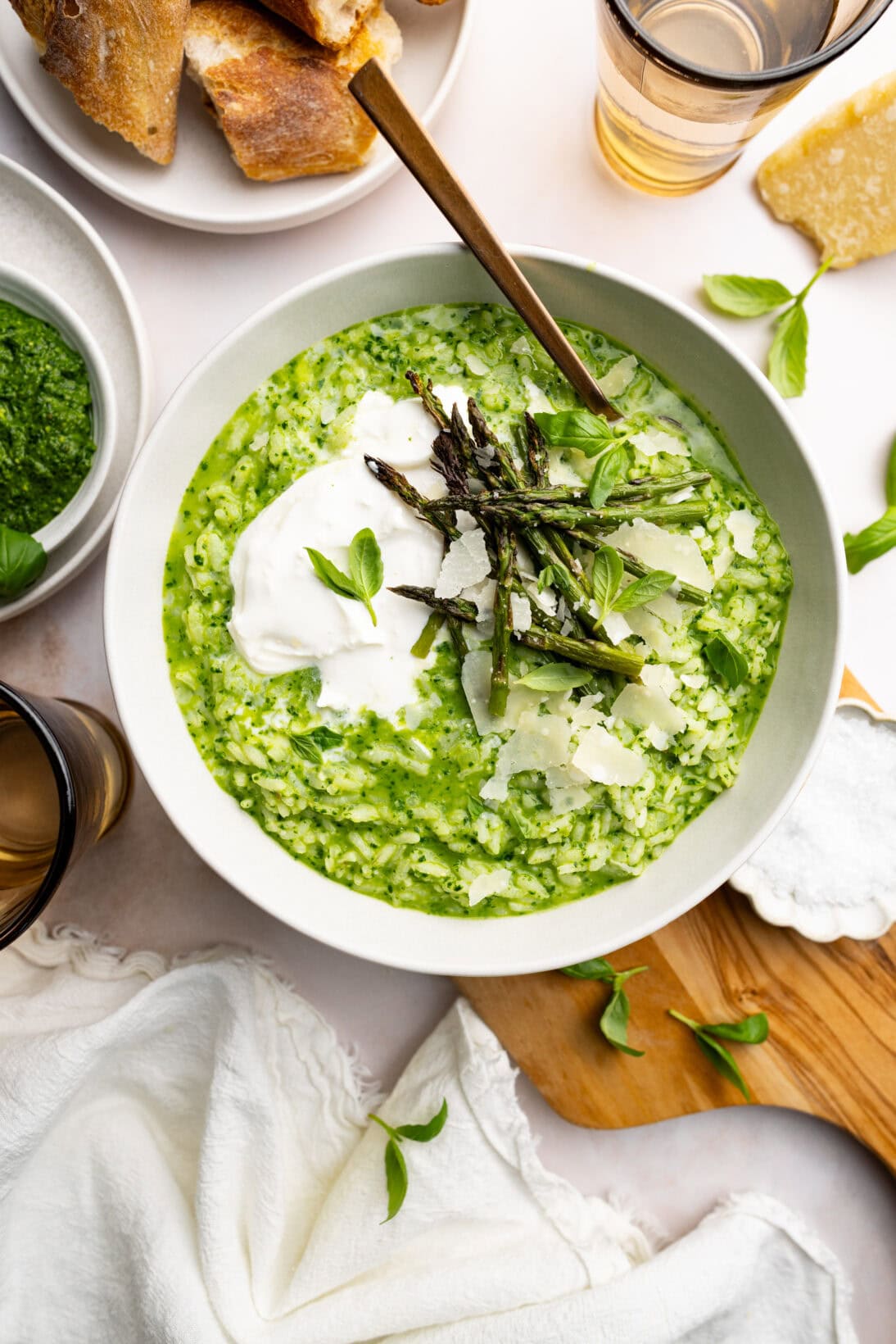 bowl of pesto risotto topped with burrata, roasted asparagus and shaved Parmesan cheese.