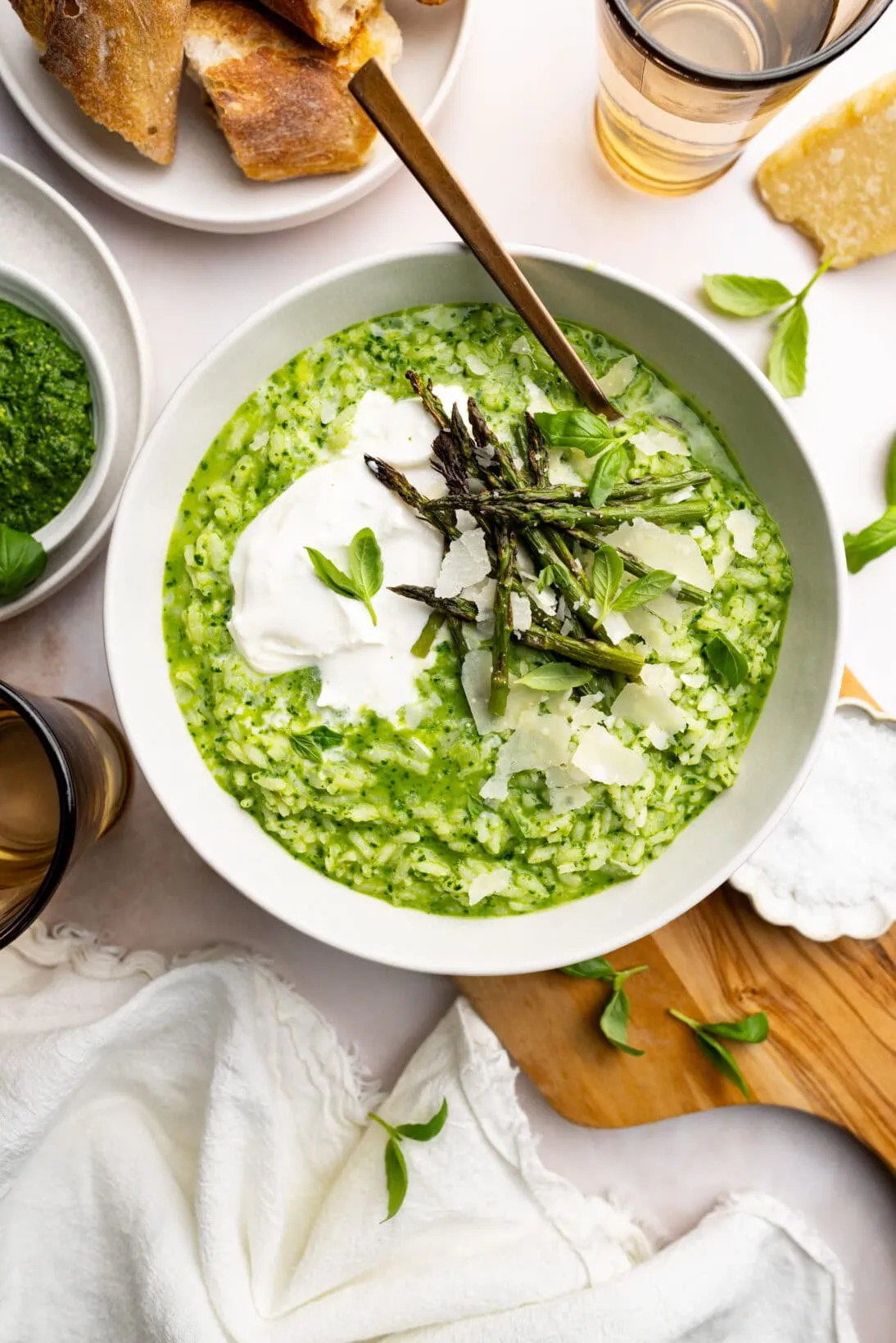 bowl of pesto risotto topped with burrata, roasted asparagus and shaved Parmesan cheese.