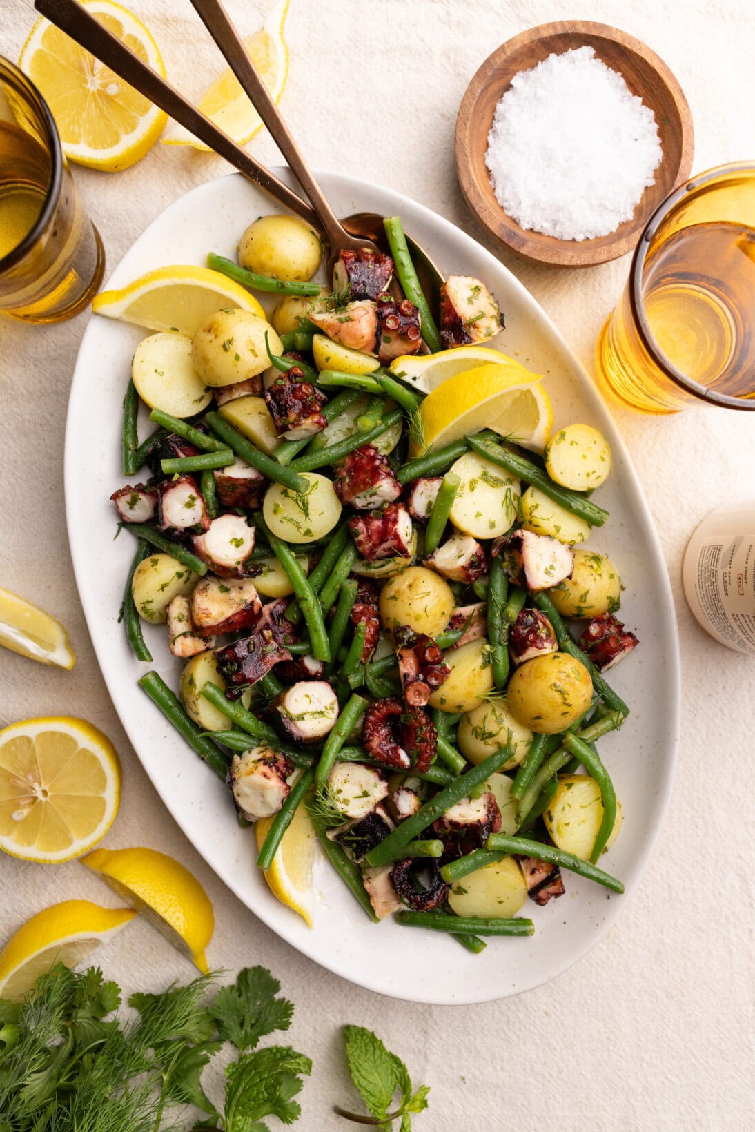 a serving plate of insalata di polpo: bite size pieces of grilled octopus with tender potatoes, french beans, coated in a lemon herb vinaigrette. 