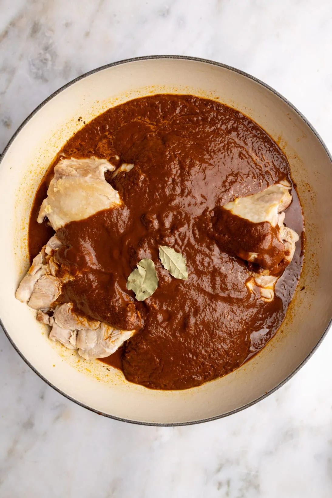step by step: adding the chicken back to the pot, strained sauce, and bay leaves.