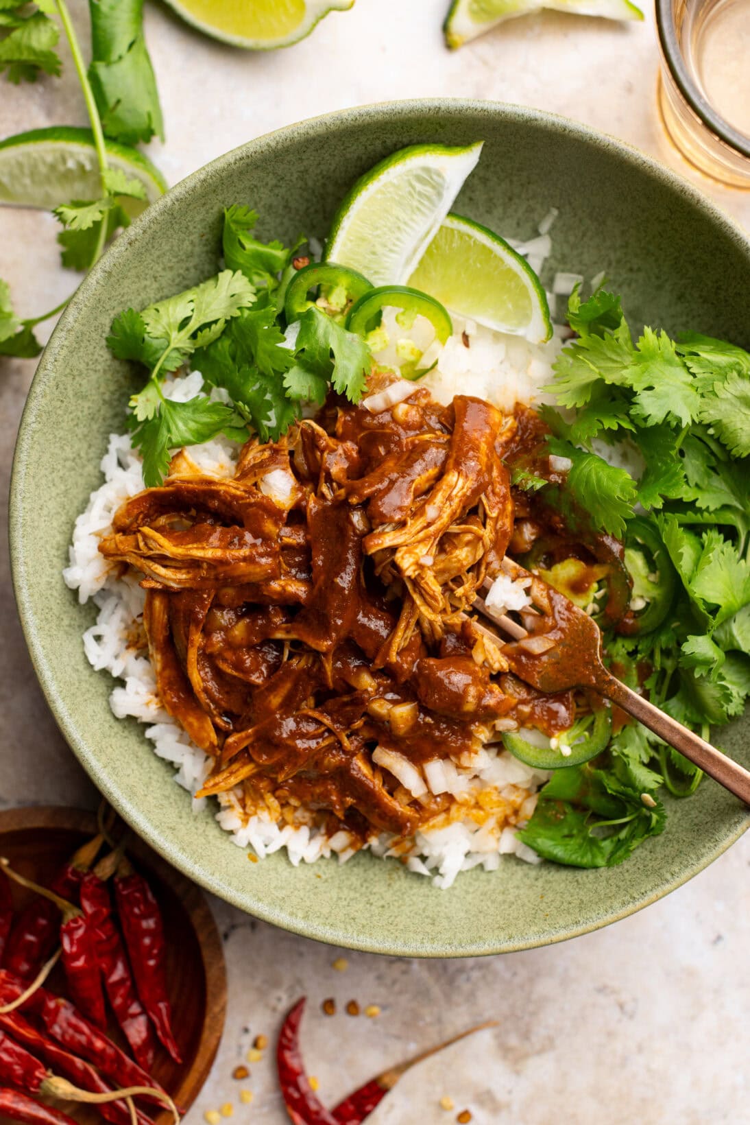 Chicken birria over white rice, topped with cilantro, white onion and lime wedges.