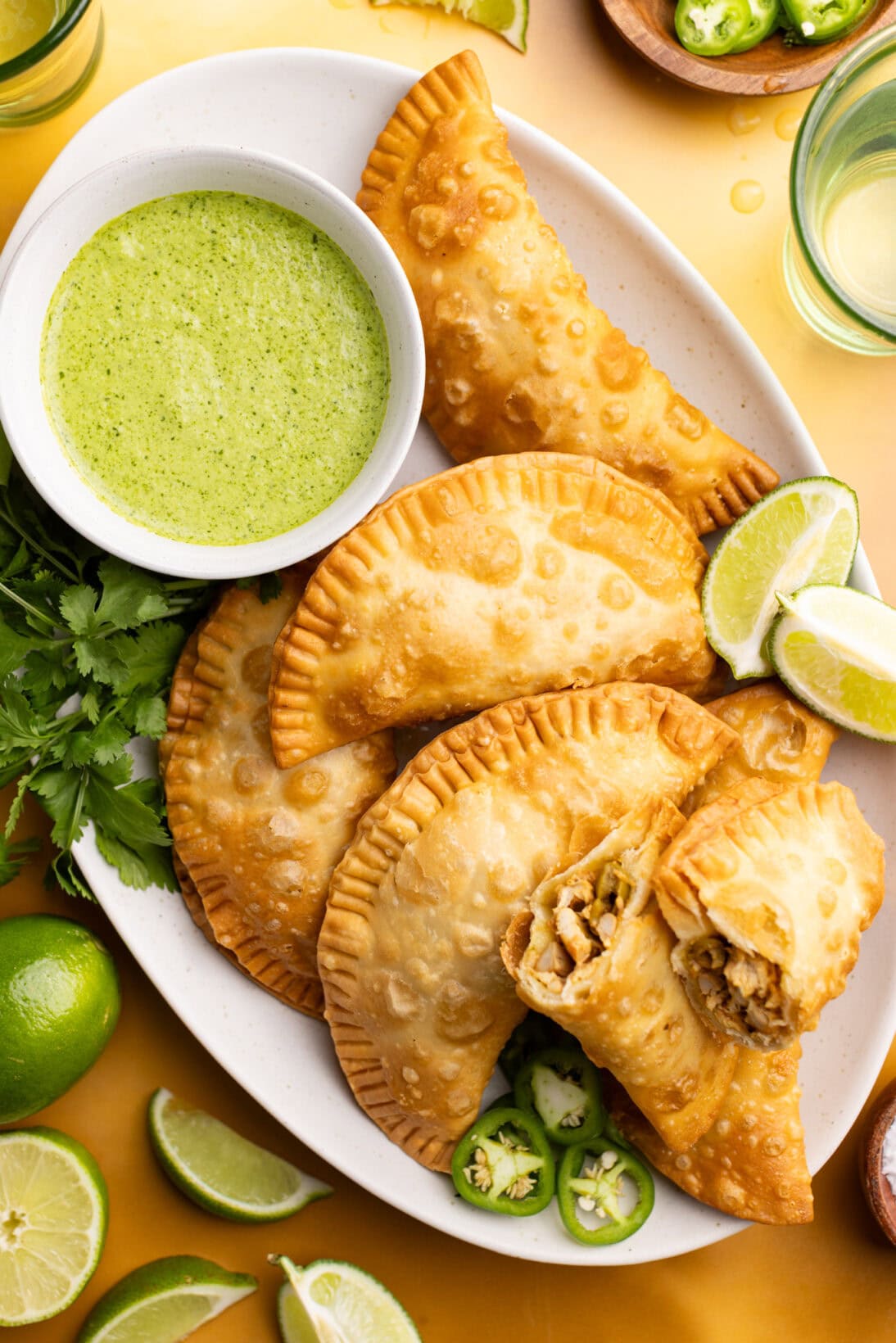 a plate of crispy chicken empanadas served with a garlic cilantro sauce.