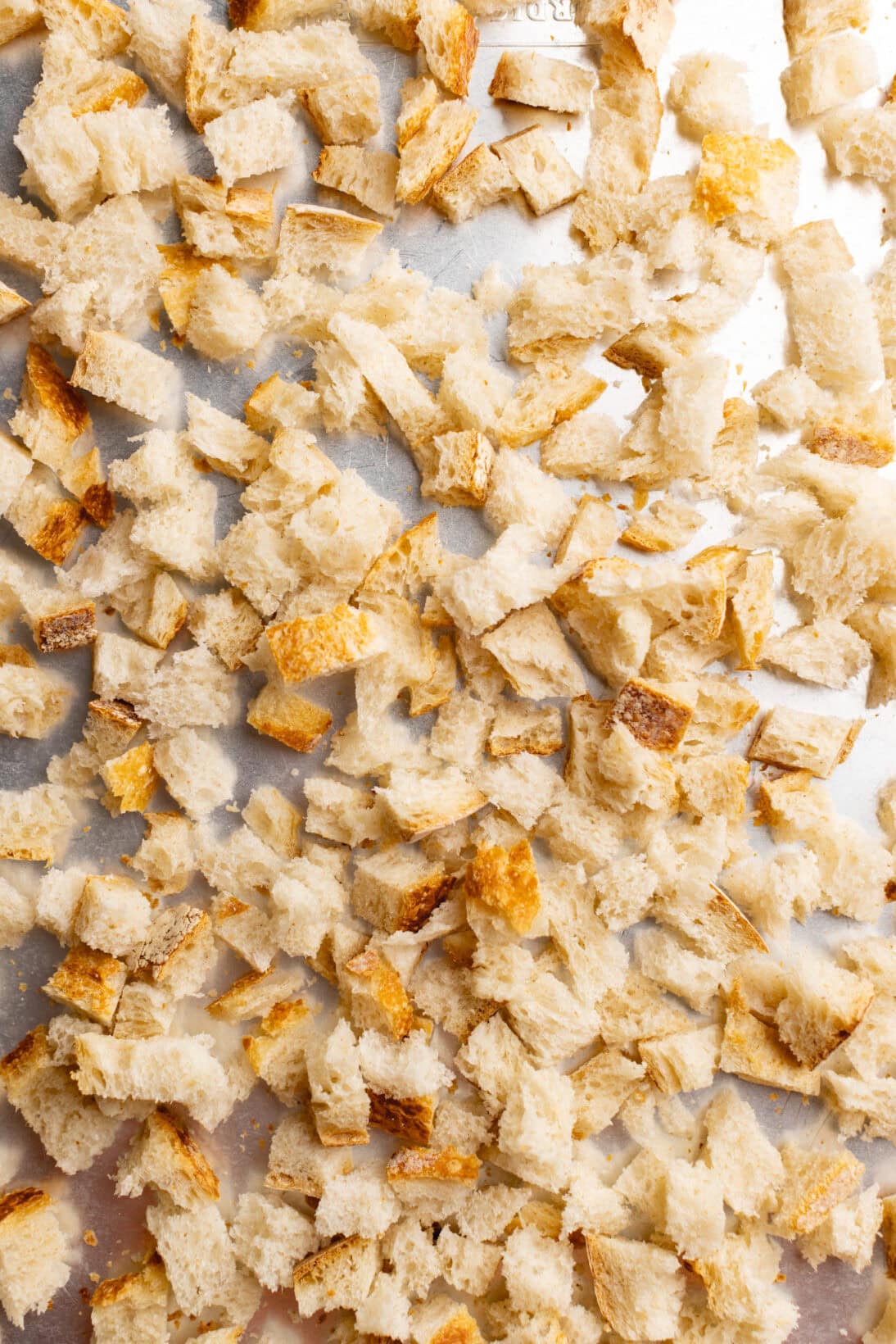 step by step: sourdough bread cut into pieces on a sheet tray.