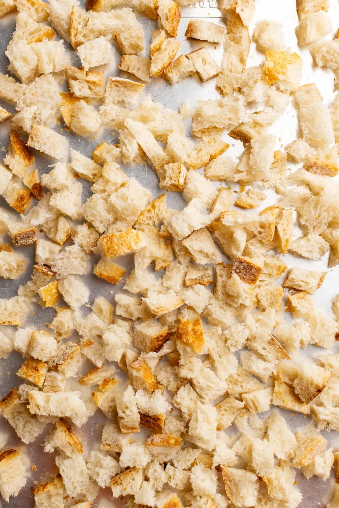 step by step: sourdough bread cut into pieces on a sheet tray.
