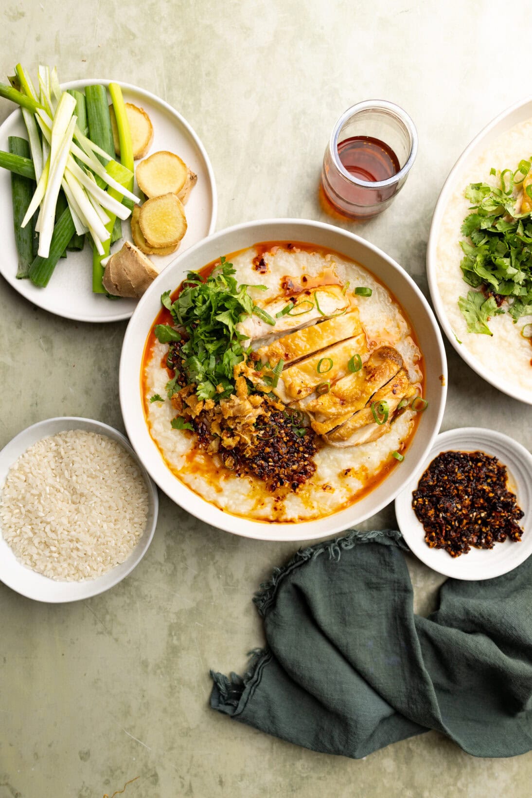 Large bowl of roasted chicken congee topped with cilantro, chili crisp, roasted chicken and chicken skin.