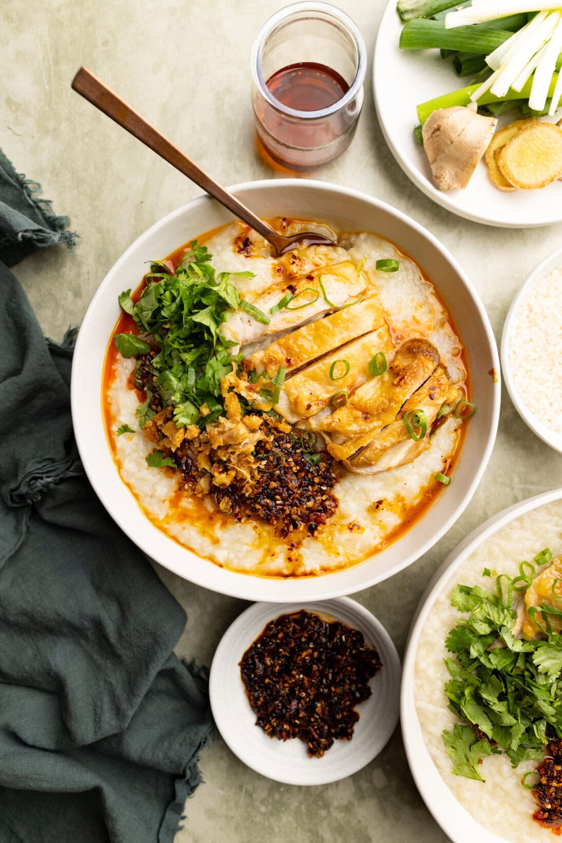 Large bowl of roasted chicken congee topped with cilantro, chili crisp, roasted chicken and chicken skin.