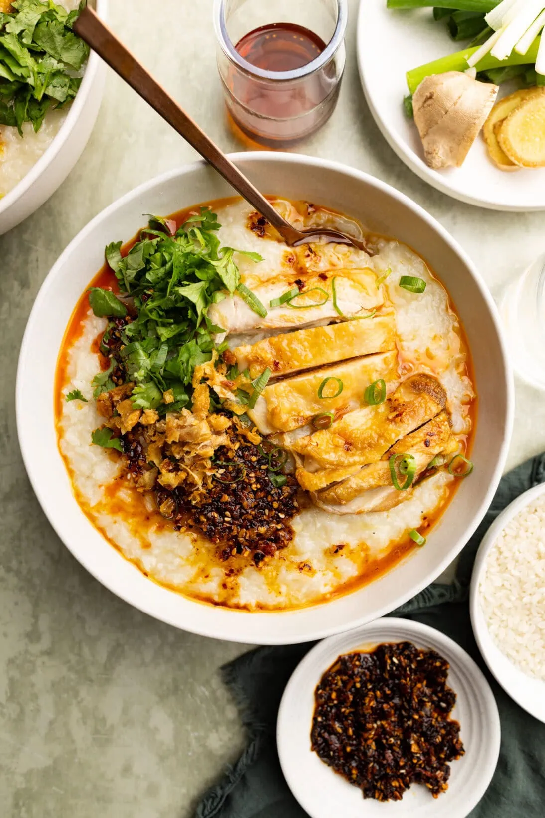 Large bowl of roasted chicken congee topped with cilantro, chili crisp, roasted chicken and chicken skin.