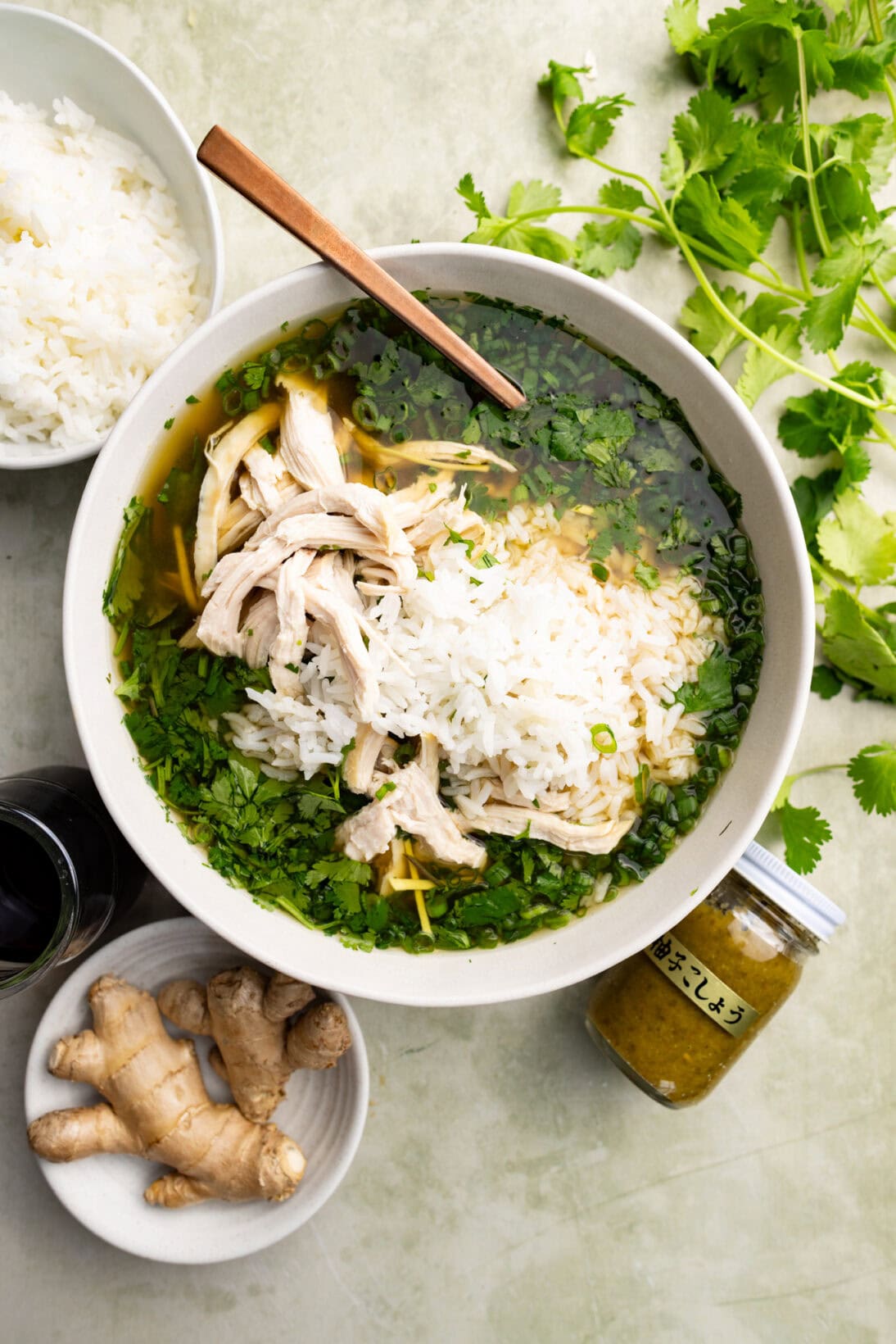 a bowl of Asian chicken and rice soup topped with extra rice and chicken.