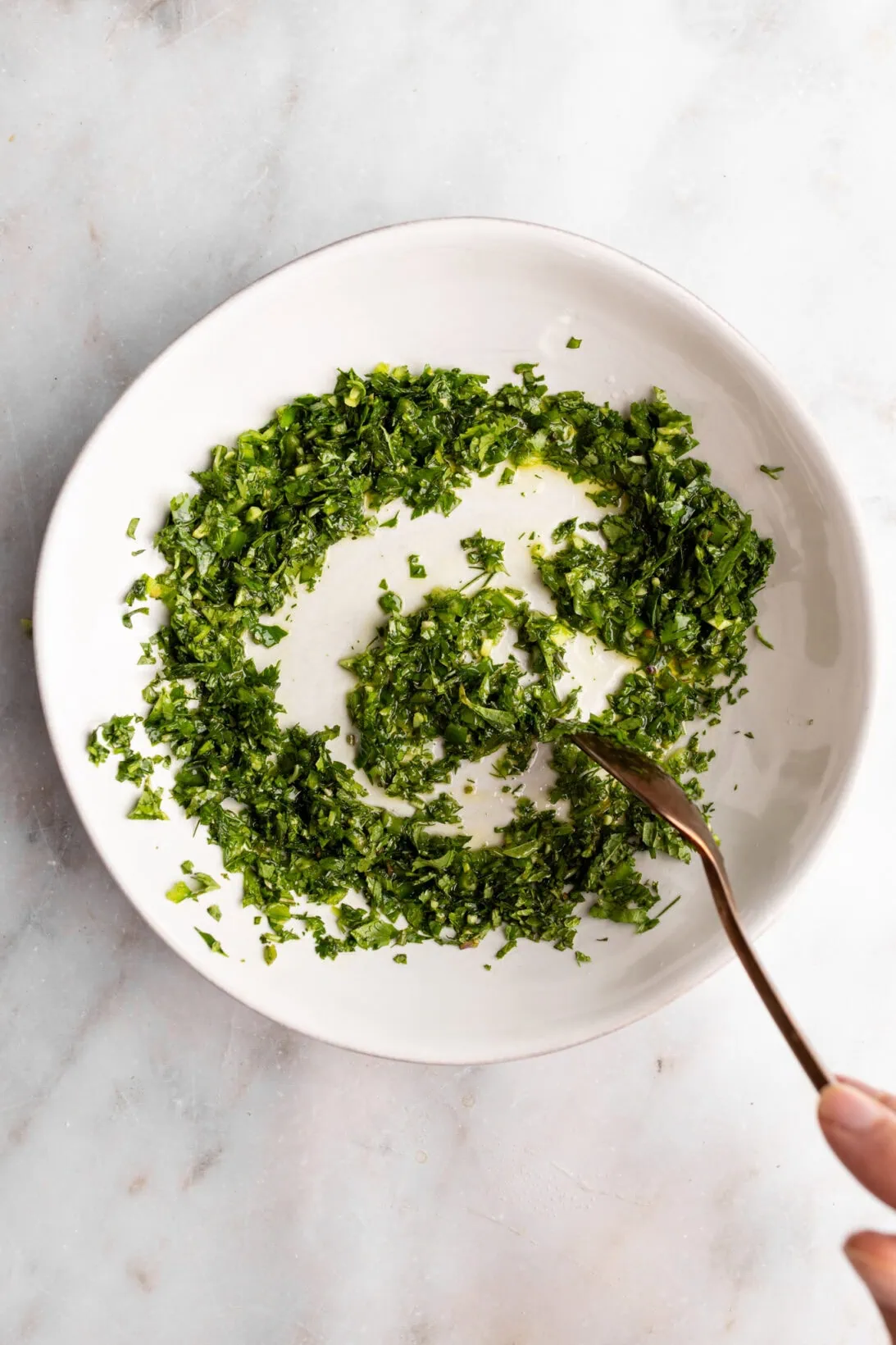 mixing the cilantro, mint, and dill gremolata