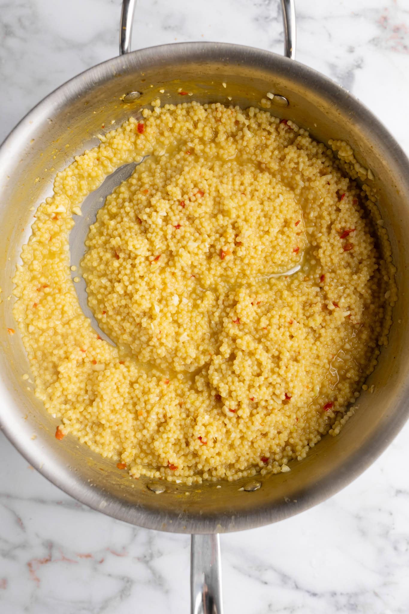 step by step: cooking the pasta in the broth until the majority of the broth has been absorbed, but the pastina is still loose.