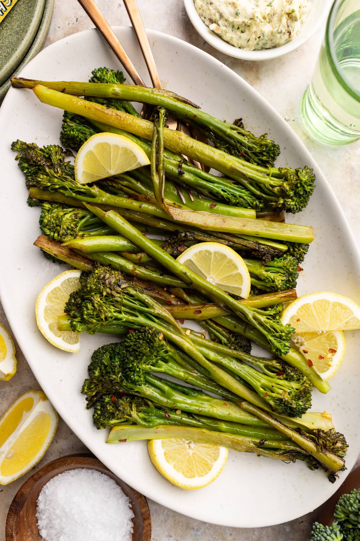 serving plate of sautéed broccolini with lemon wedges.