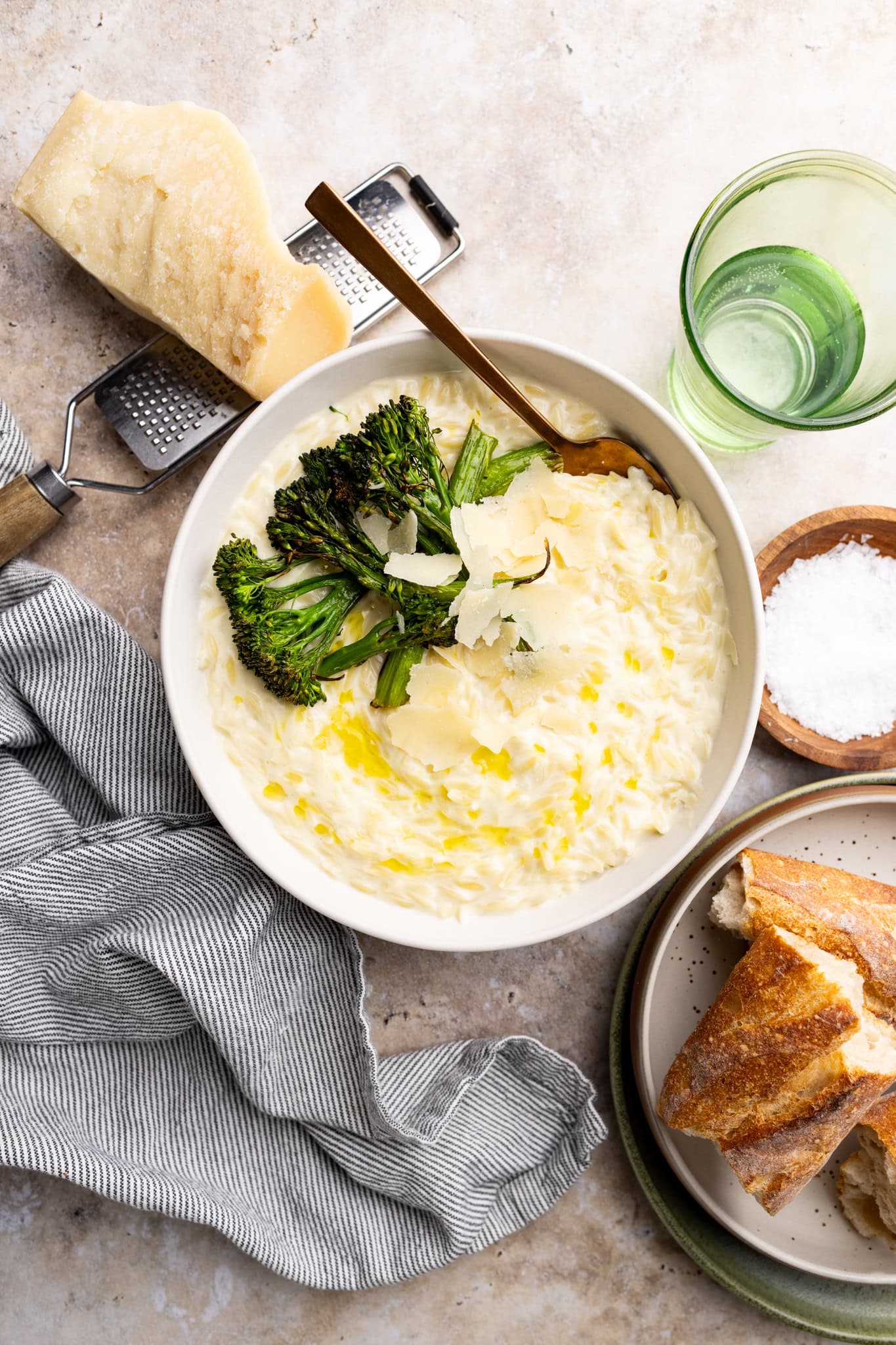 a bowl of parmesan orzo risotto topped with shaved parmesan cheese and roasted broccolini