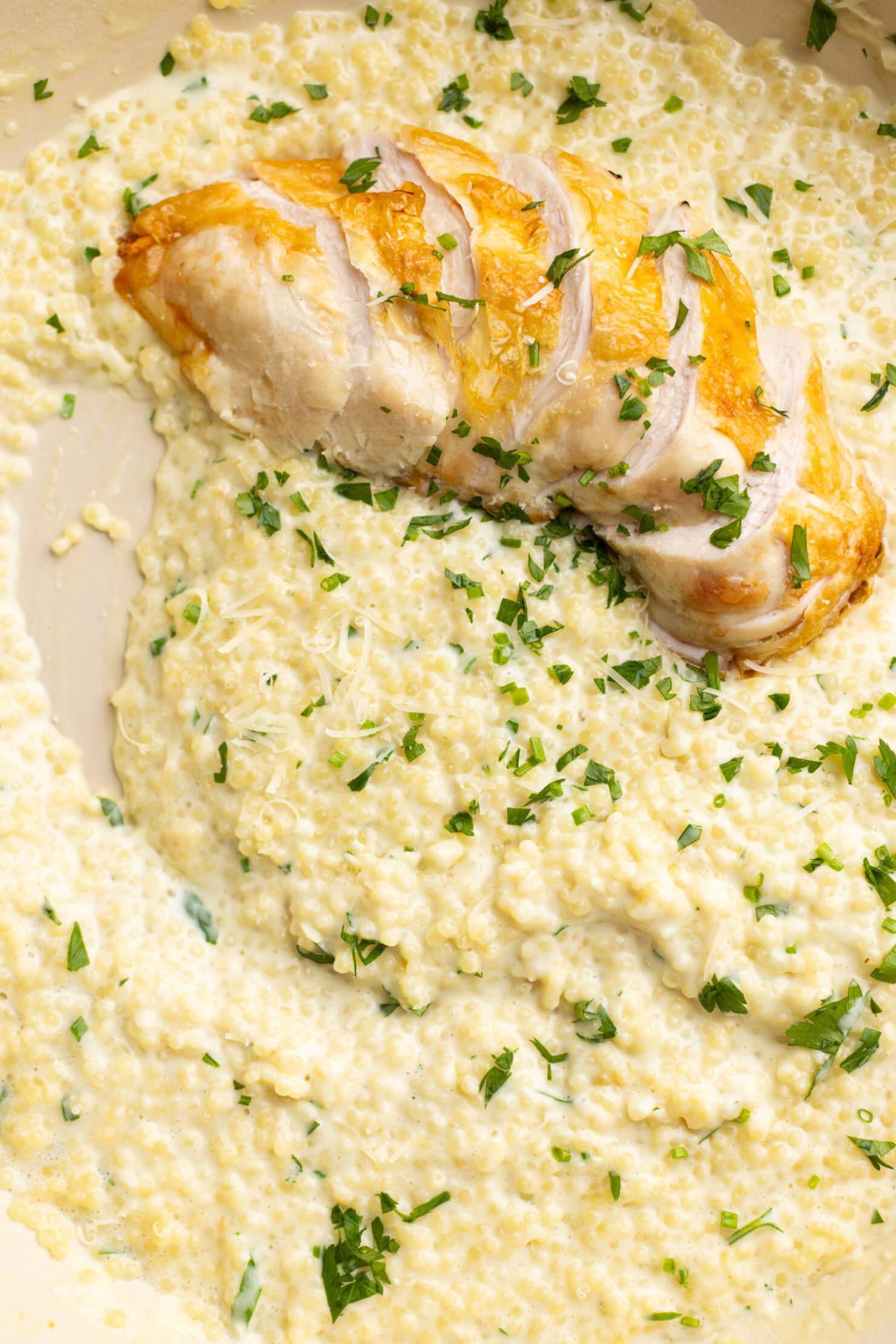 up close shot of garlic parmesan pastina topped with roasted chicken breast.