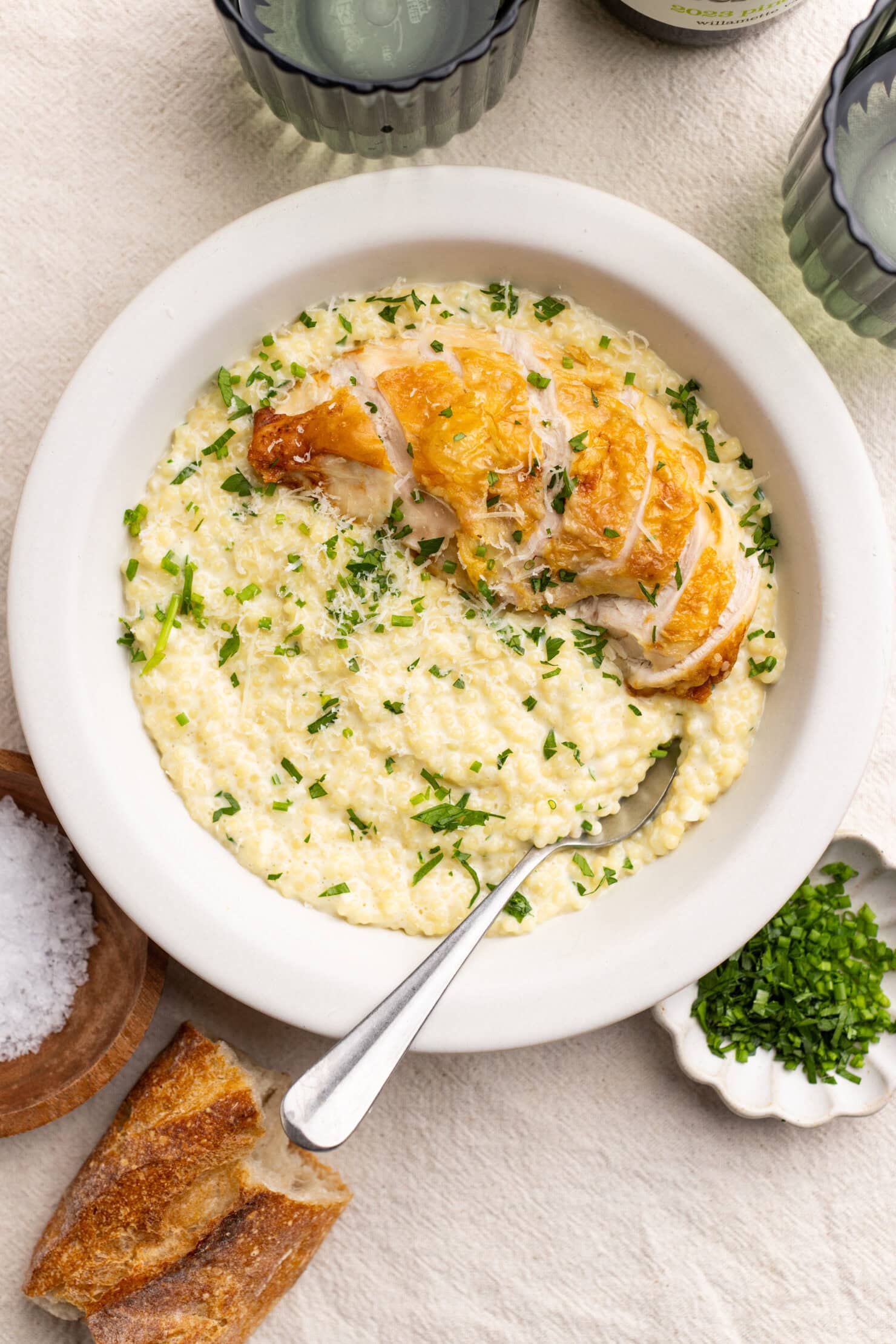 a bowl of garlic parmesan pastina topped with roasted chicken breast.