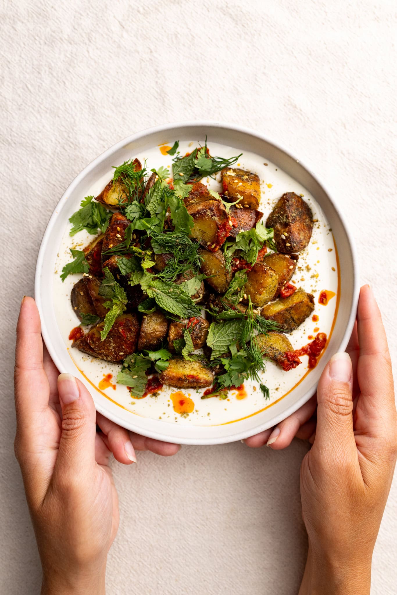 crispy za'atar potatoes over whipped feta topped with herbs and harissa.