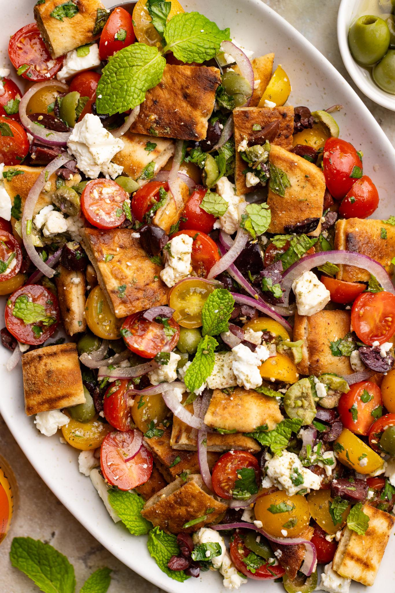 up close Mediterranean Panzanella Salad (tomatoes, onions, feta, 2 olives, and grilled pita bread)