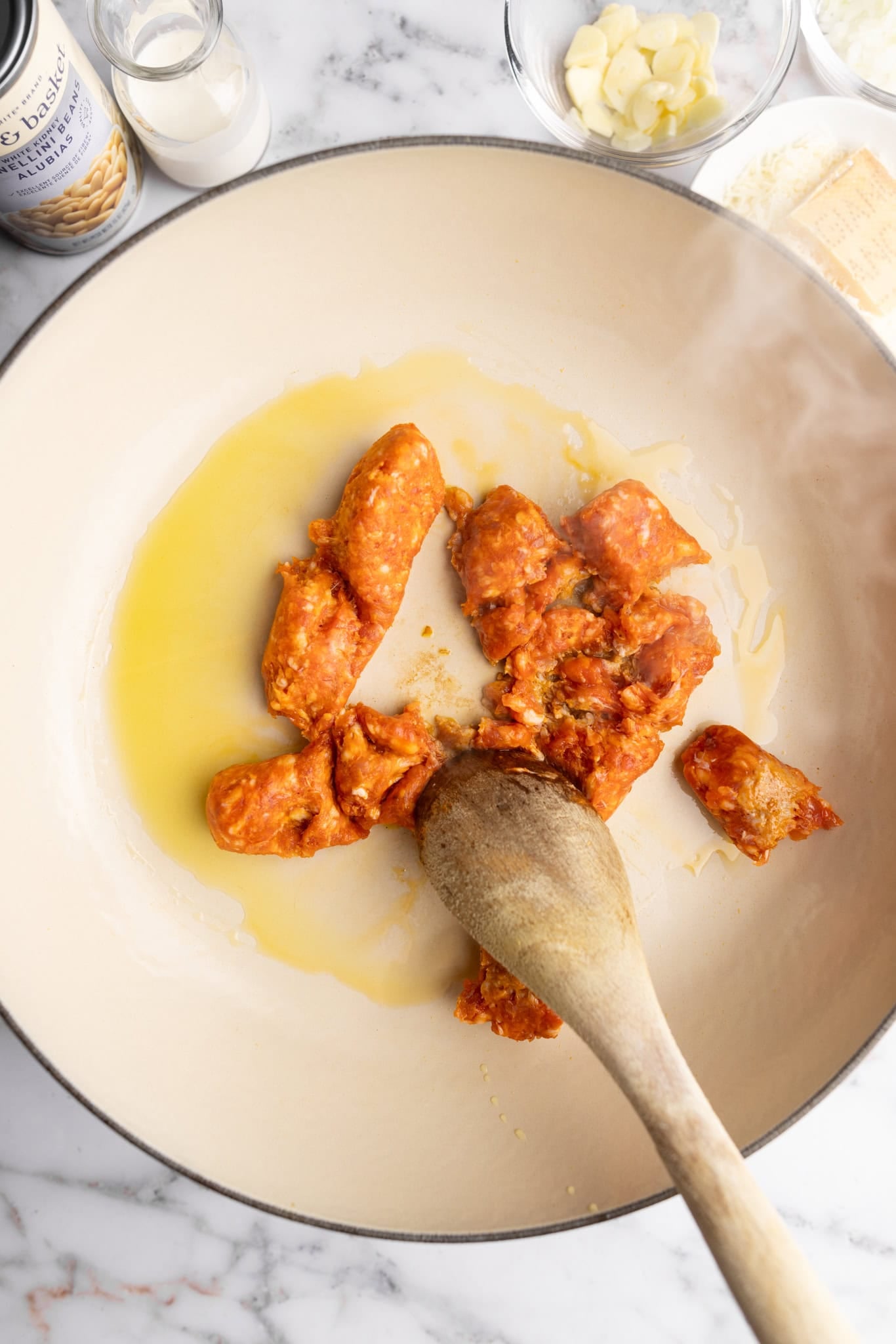 step by step: breaking the hot Italian sausage with a wooden spoon.