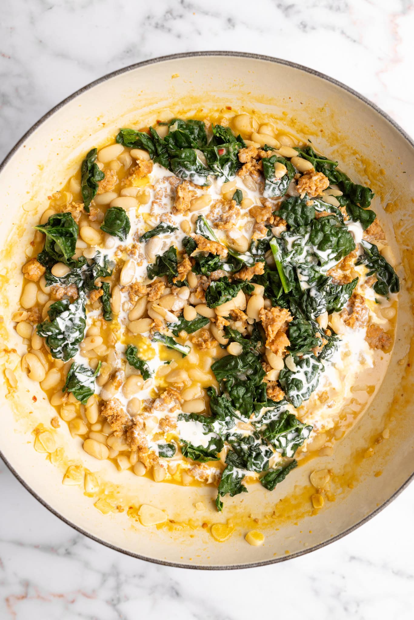 step by step: adding in the heavy cream to make the Tuscan white beans creamy.