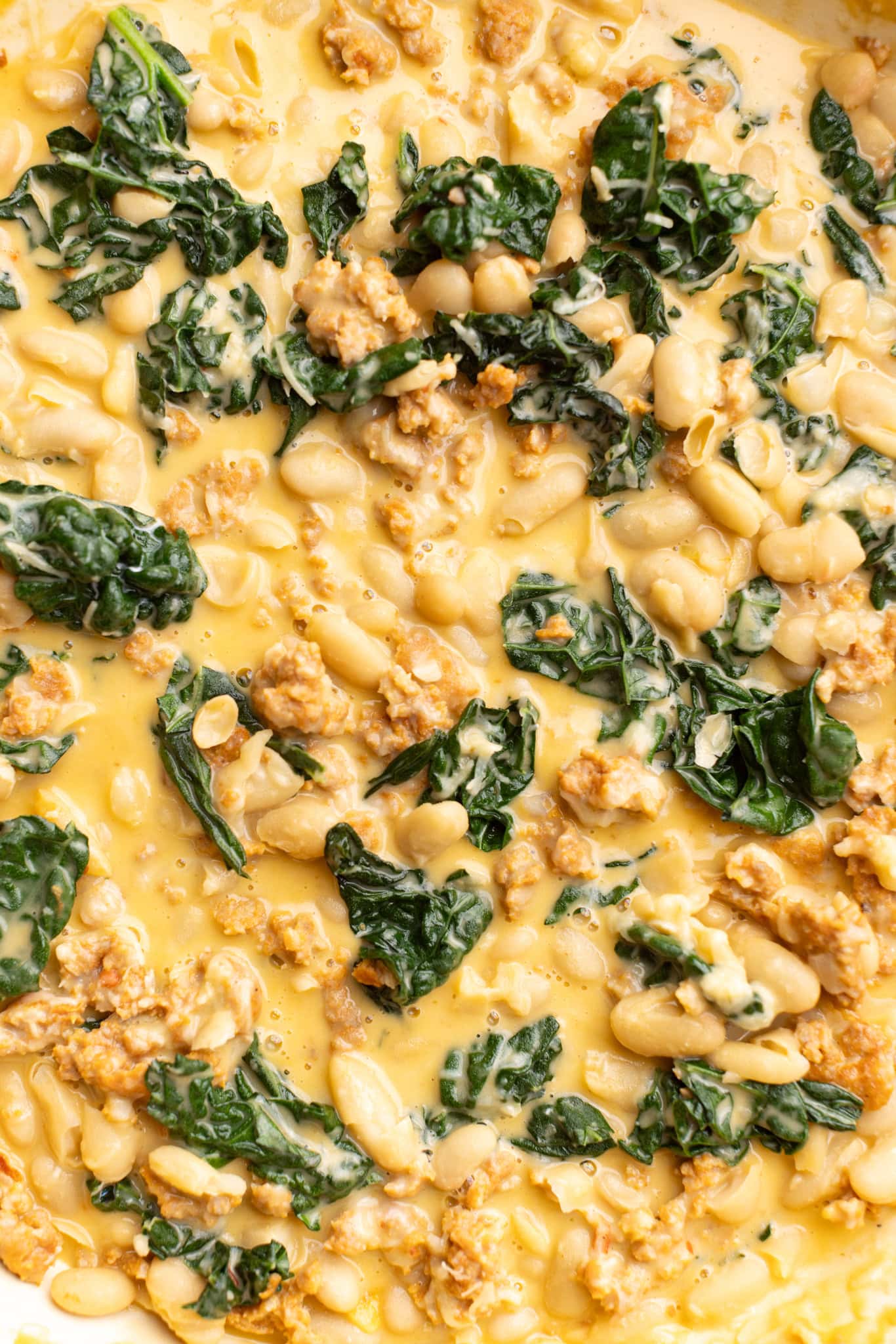 Up close shot of Tuscan white beans with spicy sausage and hearty kale.